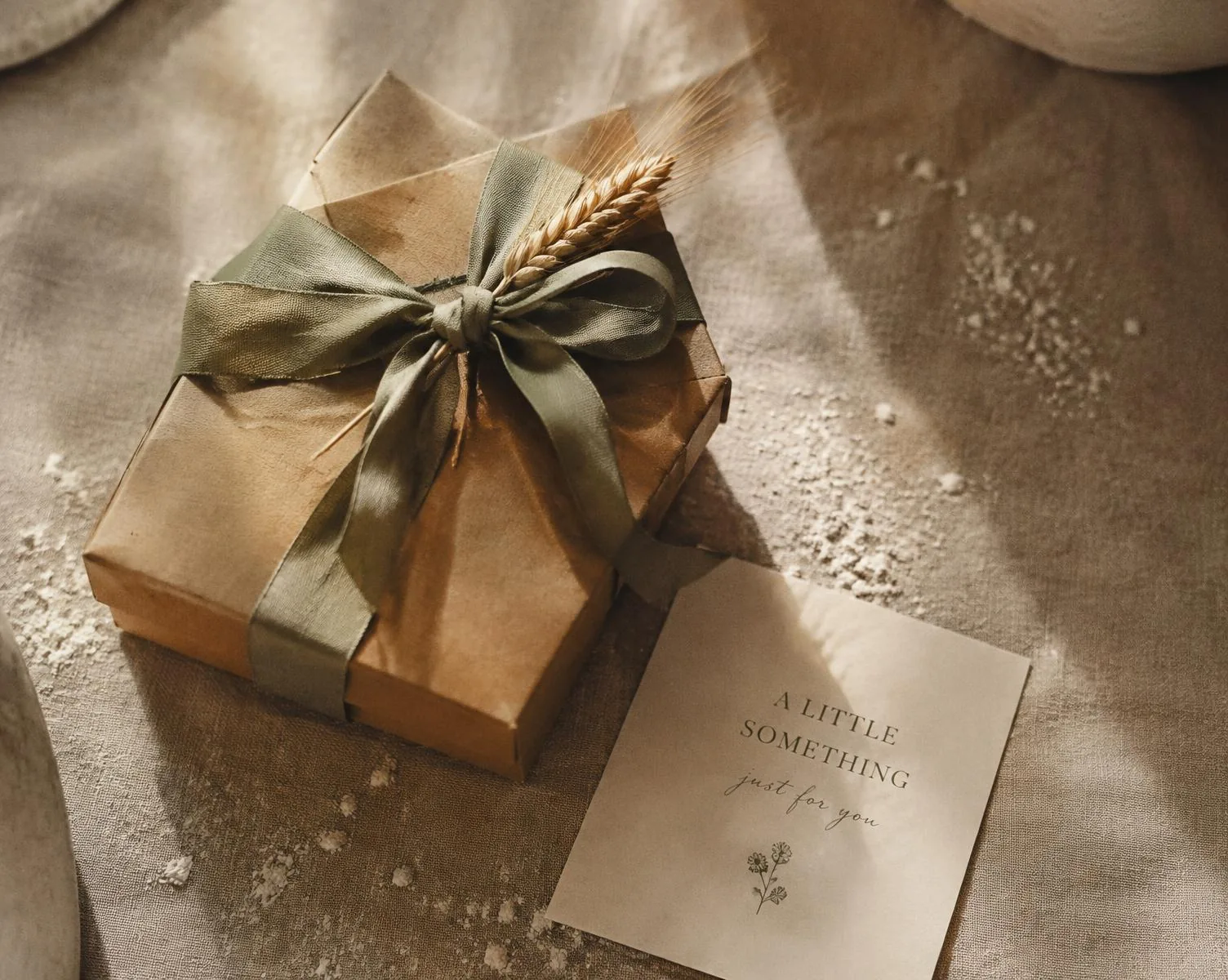 An Einkorn gift box tied with sage ribbon and a wheat sprig